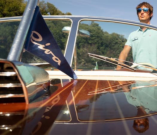 Riva Tritone luxury wooden boat sailing in Lake Como with captain and flag detail